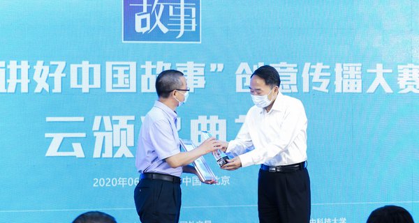 2020年6月16日，2019“讲好中国故事”创意传播大赛云颁奖典礼暨2020年度大赛云启动仪式在北京举行。图为中宣部副部长蒋建国（右）为特等奖作品《胡同里的外国志愿者》颁奖。